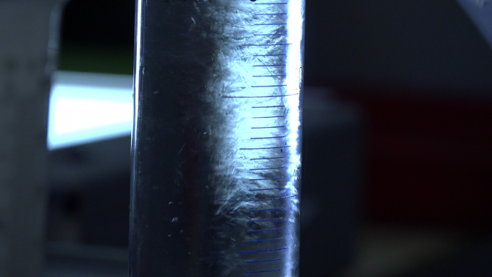 Still from the film Een Donker Uitzicht. It's a extreme close-up of a vial with developing liquid, used to develop film. It looks dreamy, almost magical.