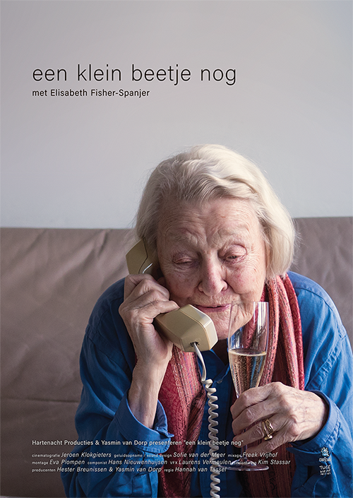 Poster from the film Een klein beetje nog. Elisabeth is sitting on her couch with her phone in one hand and a glass of champagne in the other.