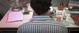 Still from the film Nowhere Place. The writer is sitting in front of the typewriter and we are seeing the back of his head and his shoulders.