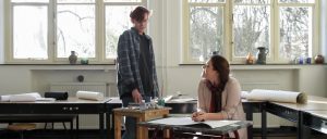 Still from the film Ne Me Quitte Pas. Patrick and Angelique are sitting and lying on the worktables in an art workroom.