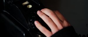 Still from the film Ne Me Quitte Pas. It's a close-up shot of Patrick's hand on the dial of an old rotary phone.
