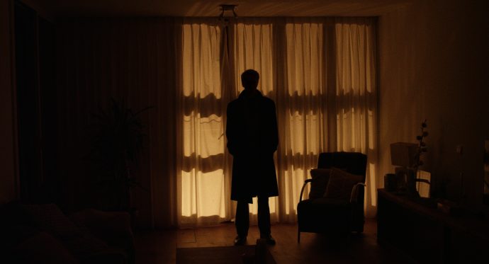 Still from the film Van Binnenuit. A silhouette is standing in a living room.