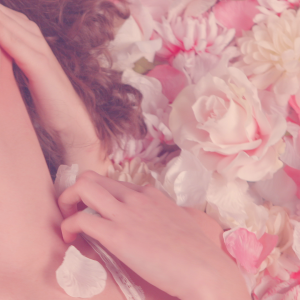 Still from experimental film Verbeelding 2. It's a close-up focused on a bed of pink and white roses with a head of a girl laying on top of it. The girl is almost out of frame and the neck is exposed.