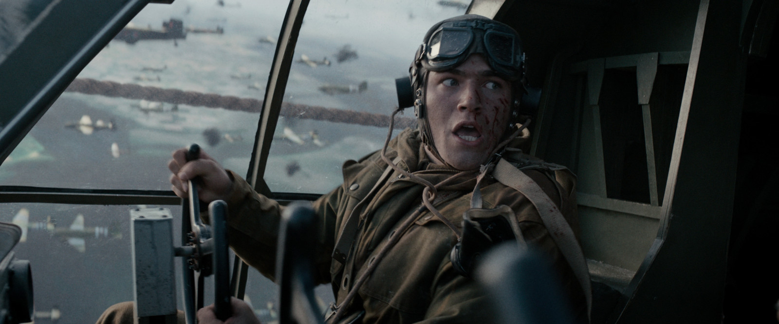 Still from the film De Slag om de Schelde/The Forgotten Battle. William is in his seat in the cockpit of a WW2 fighter plane. He's looking behind him with shock, blood on his face. Through the window you can see more planes.