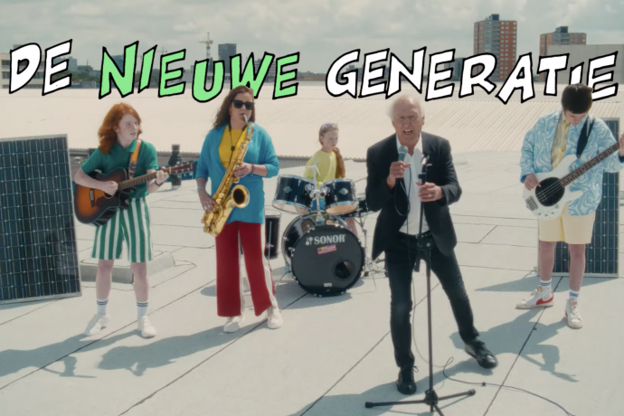 Still from 'Kom Van Dat Gas Af'. It's a wide shot of a band on a flat rooftop. The singer is an old white man, Peter Koelewijn. Behind him from left to right: a young boy with long ginger hair and a green outfiton guitar, a young woman with a saxophone, long brown hair and sunglasses, a young ginger girl on the drums wearing a yellow shirt, and a young man with short black hair playing the bass. There's comic book style text above them saying 'DE NIEUWE GENERATIE'.